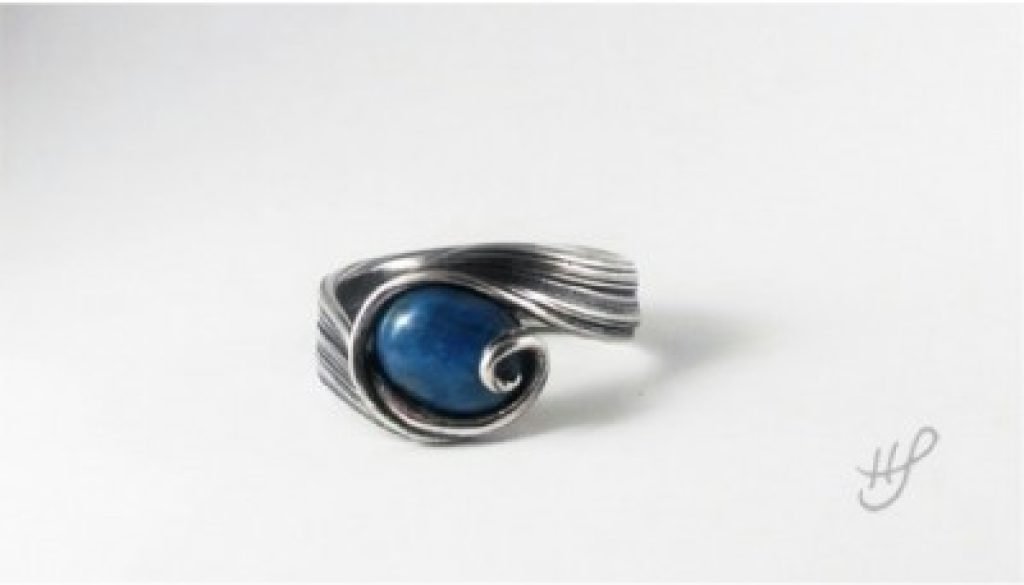 Silver ring with a wave design over a denim lapis stone.