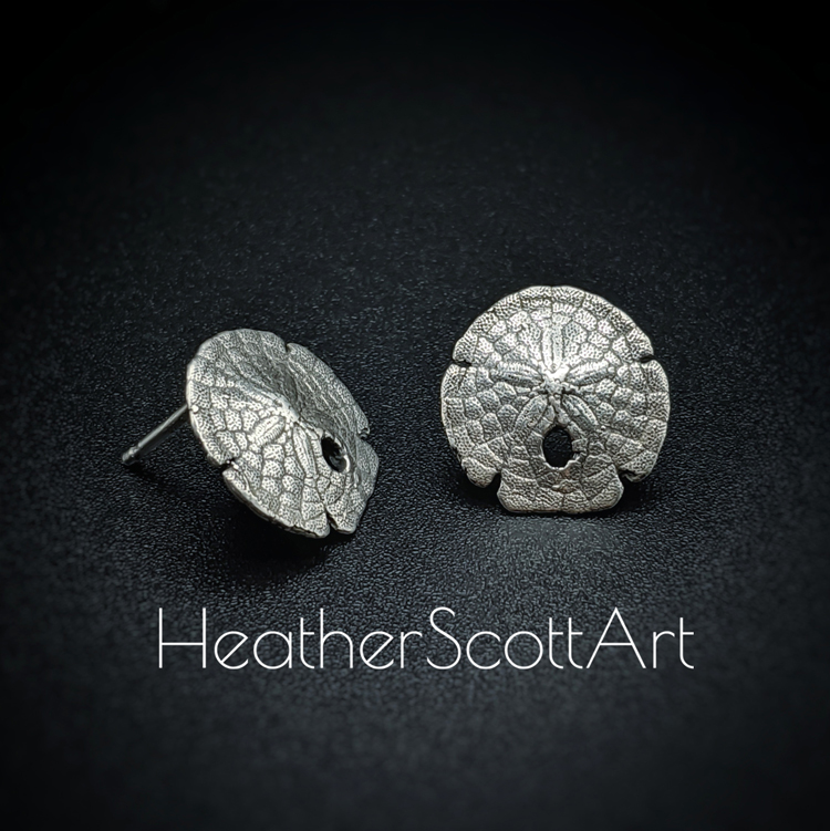 Small sterling silver sand dollar stud earrings sitting on a black background with the words Heather Scott Art in the foreground.