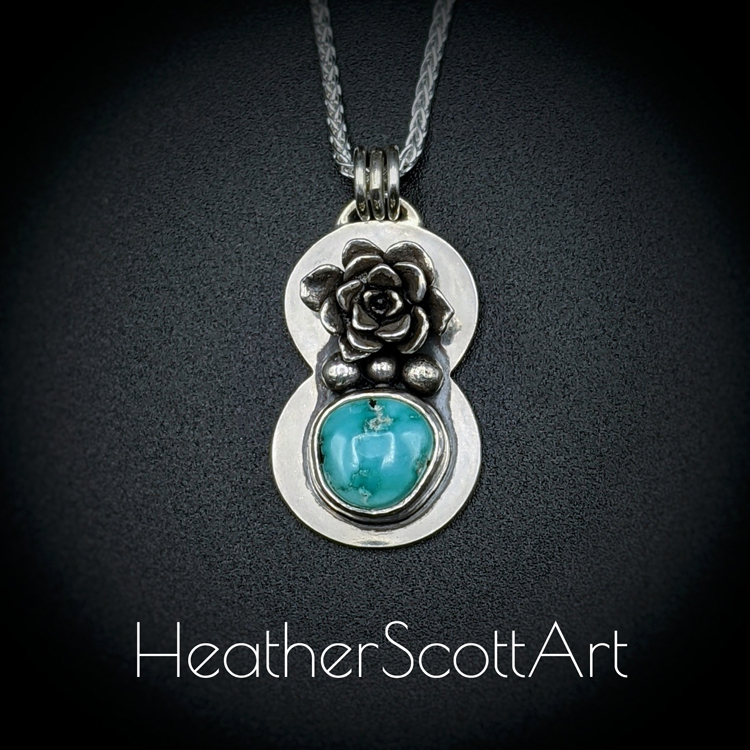 A handmade pendant in stering silver showing a succulent sitting above a turquoise stone with 3 dots between the succulent and the stone. The pendant is hanging from 3 jump rings attached to a sterling silver chain. It sits against a black background with the words Heather Scott Art in the foreground.