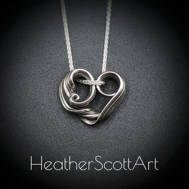 Sterling Silver heart with a twisted side and linear textures.