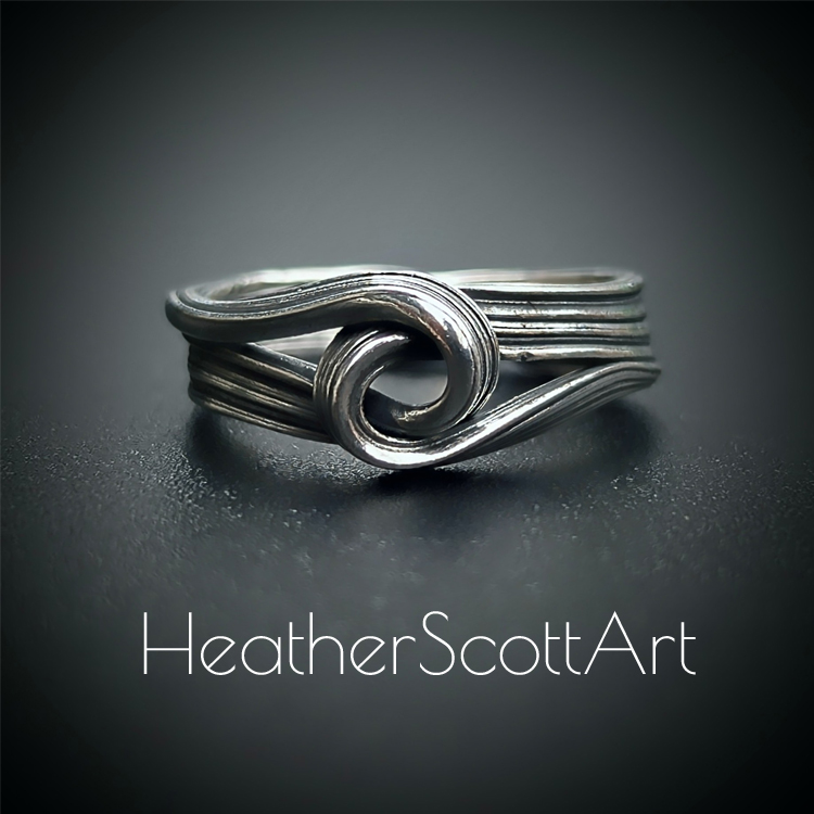 Close-up of a handcrafted knot ring with a linear texture, flowing design, created using the Mitsuro technique, displayed on a dark background.