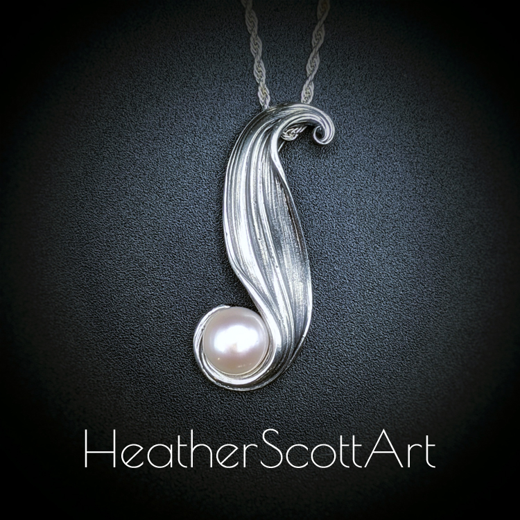 A pendant with textural lines holding a freshwater pink pearl.