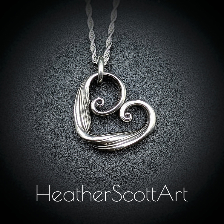 Sterling Silver heart pendant with spirals and linear textures on a rope chain.